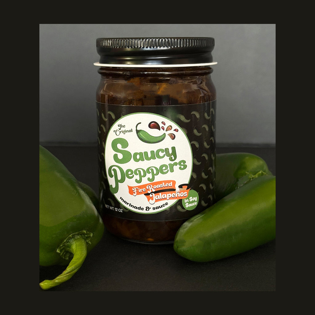 Jar of 'Saucy Peppers' fire roasted jalapenos with jalapeno peppers on a dark background
